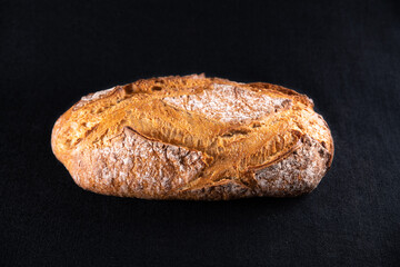 Rustic bread, beautiful golden crust with diamond patterns, top view, on black background	