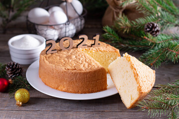 New Year and Christmas sponge cake or chiffon cake on white plate so soft and delicious with ingredients: eggs, flour, milk on wood table.