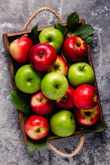 Ripe red and green apples in wooden box.