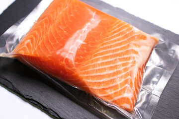 Fresh salmon fillet in vacuum package isolated on black plate for delicious salmon steak. 