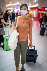 A young woman wearing face mask before traveling on airplane , New normal travel after covid-19 pandemic concept. woman in the airport ready to fly wearing mask