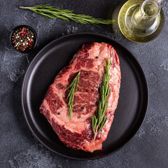 Fresh raw beef steak on black plate.