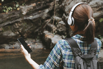 Young woman tourist traveling backpack enjoying adventure using headphone listening to music.selective focus.