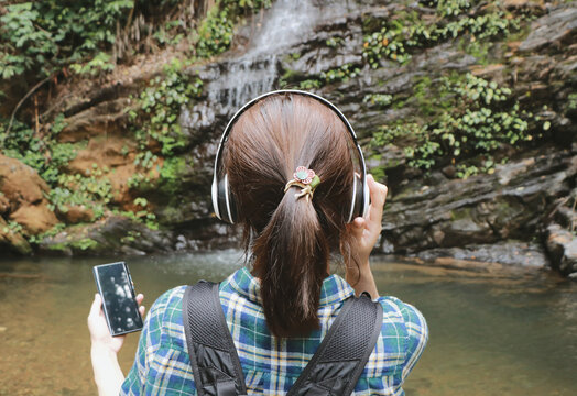 Young woman tourist traveling backpack enjoying adventure using headphone listening to music.selective focus.