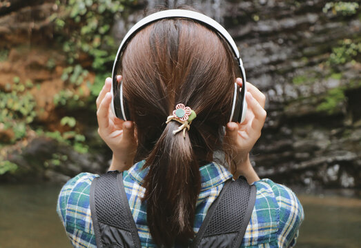 Young woman tourist traveling backpack enjoying adventure using headphone listening to music.selective focus.