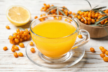 Fresh sea buckthorn tea on white wooden table, closeup