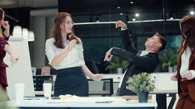 Happy satisfied business people have fun dancing and celebrating success. Colleagues rejoice, laugh and enjoy the victory
