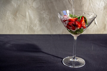  cooling strawberry cocktail with ice and mint on black and concrete background, stylish and tasty, unusual martini