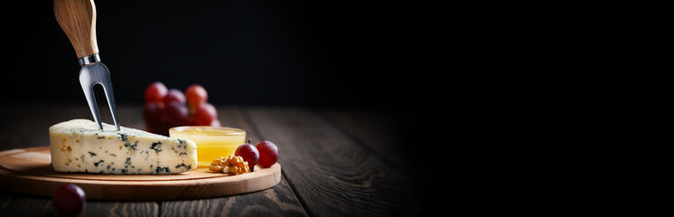 Blue cheese with fork on cut wooden board