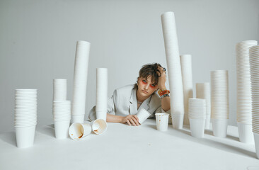 Tired girl and lots of paper cups for coffee. Hard morning, chronic lack of sleep and caffeine...