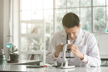 scientist man using microscope in laboratory(vintage tone)