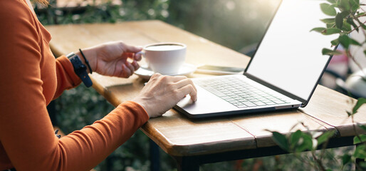 Cropped shot of young businesswoman working on her laptop while sitting outdoors at a cafe
