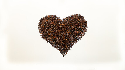 Roasted coffee beans, arranged in a heart shape, on white background	