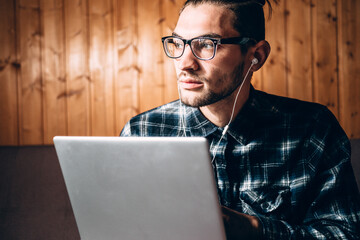 Remote work during the quarantine. A handsome young freelancer in a blue shirt and glasses with...