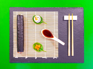 Présentation de plat de cuisine Japonaise, dés de saumon, sushi et maki sur fond noir avec sauce soja.