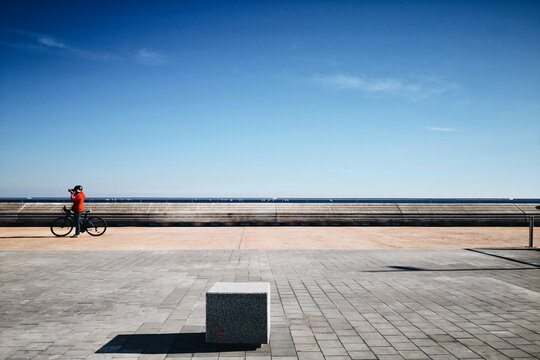 Mujer con un abrigo rojo tomando fotos sobre una bicicleta.