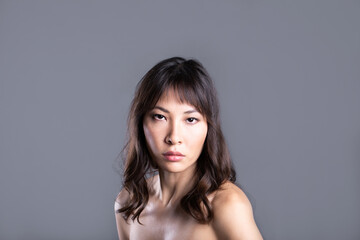 Obraz na płótnie Canvas Portrait of a beautiful attractive Asian woman on gray.