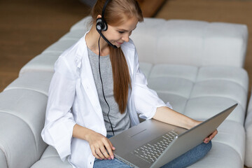Smiling millennial woman student in headphones using laptop.