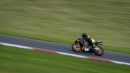 A panning shot of a racing bike cornering as it circuits a track.