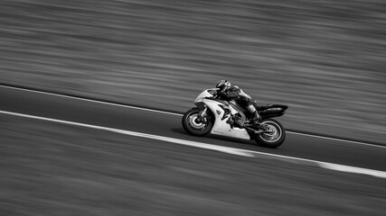 Obraz premium A monochrome panning shot of a racing bike cornering as it circuits a track.