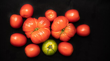 Different varieties of tomatoes, on black background	