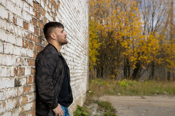 Fototapeta na wymiar Bearded man against a brick wall. Autumn photo.