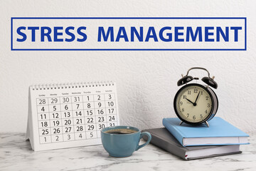 Text Stress Management over table with calendar, alarm clock, notebooks and cup of coffee