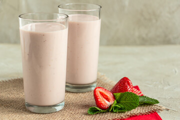 delicious milkshake with strawberries in tall glasses, strawberries and mint, burlap napkin create a cozy atmosphere