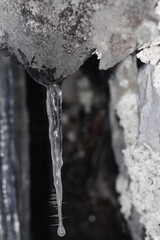 Singe crystalline Icicle hanging from rock in winter creating a frosty mood