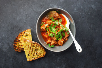 Slow cooked pork with vegetables, carrots, onions and ripe tomatoes with sweet peas and bay leaves in a plate. View from above. Comfortable homemade food.