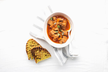 Slow cooked pork with vegetables, carrots, onions and ripe tomatoes with sweet peas and bay leaves in a plate. View from above. Comfortable homemade food.