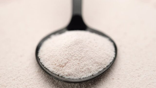 close up collagen powder in spoon on collagen powder background, left rotating. Natural beauty and health supplement