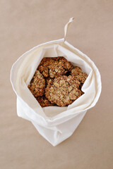 Reusable bag with homemade oats cookies on brown background. Healthy eco life concept. 