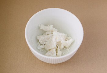 White plate with solid coconut oil on beige background. Minimalistic style. Kinfolk concept. 