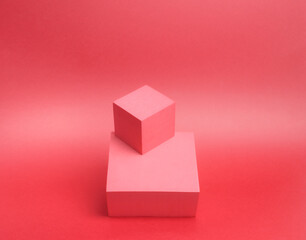 Fototapeta premium Photo of a bright podium (pedestal) of two cubes on a paper background. In pink, with gradient. Advertising place. Blank product stand and abstract background with light.