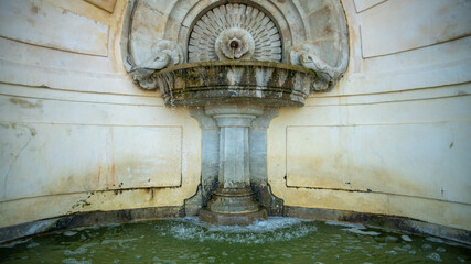 Close-up on the water that springs from a city wall fountain, in stone, beautifully crafted	