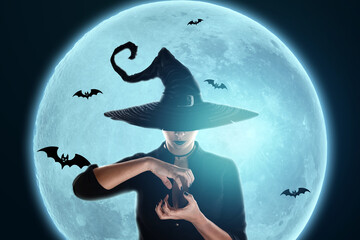 Halloween witch girl conjures against the background of the moon. Beautiful young woman in a witch...