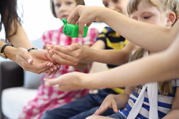 Obraz na płótnie Canvas Green jar with hand sanitizer. Children and women put hands together for germ treatment