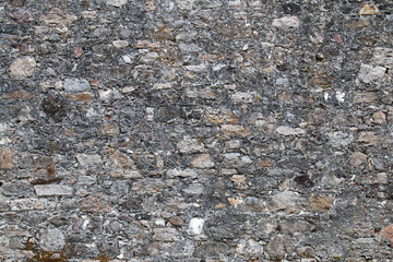 old wall made of multicolored stones sealed with cement