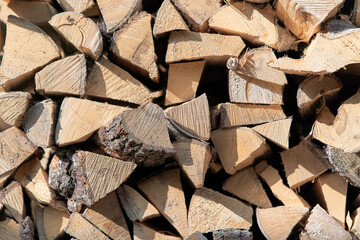 Chopped firewood stacked in a woodpile, view from the end of the masonry