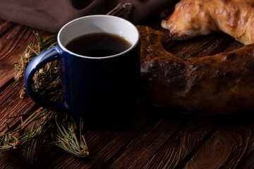 Homemade pastries and a cup of tea on an old wooden surface. Homemade strudel. Anise and fragrant herbs on the table. Low key photo.
