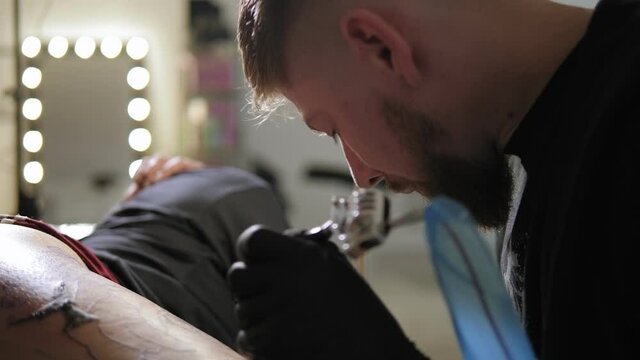 A tattoo master with a beard who holds in his hand Tattoo machine.