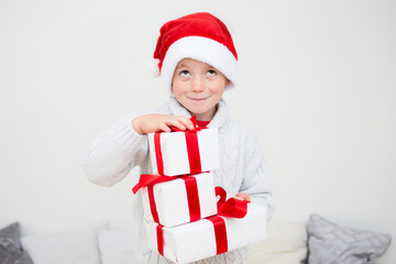 Excited smiling little boy in red santa hat with gift many boxes isolated on white background, banner copy space. Christmas congratulation concept.