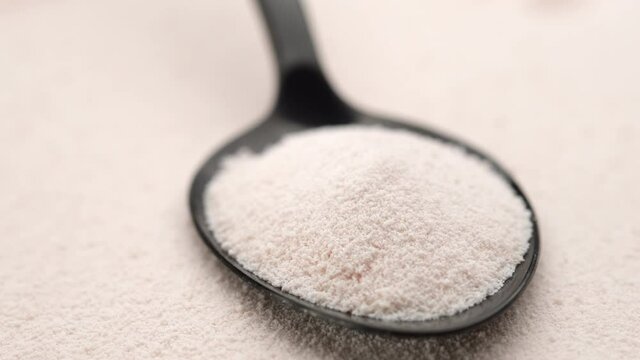 close up collagen powder in spoon on collagen powder background, left rotating. Natural beauty and health supplement