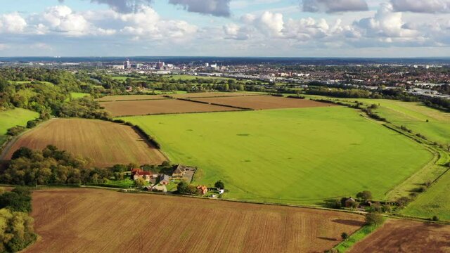 4k aerial footage moving over countryside farm fields towards the town of Reading, Berkshire, UK