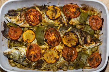 baked fish dish, Mediterranean food, baked sea bass with tomatoes and potatoes 