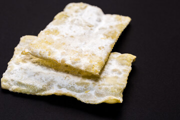 traditional sweet crisp pastry, deep fried for Carnaval, Italian chiacchiere on the black background
