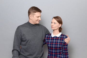 Portrait of serious woman and joyful man hugging and looking at each other