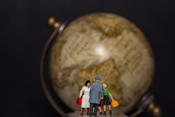 Miniature travelers and a global in background, travel and immigration concept
