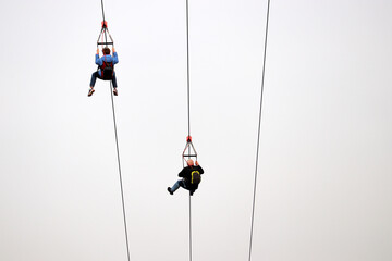 Couple on the zipline on sky background, bottom view